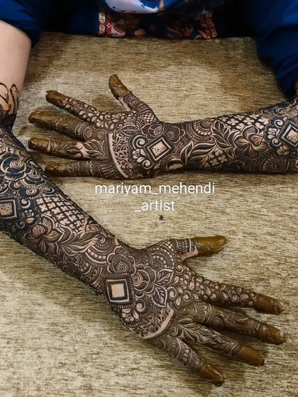 A classic bridal mehendi with geometric and floral patterns, covering the arms completely.