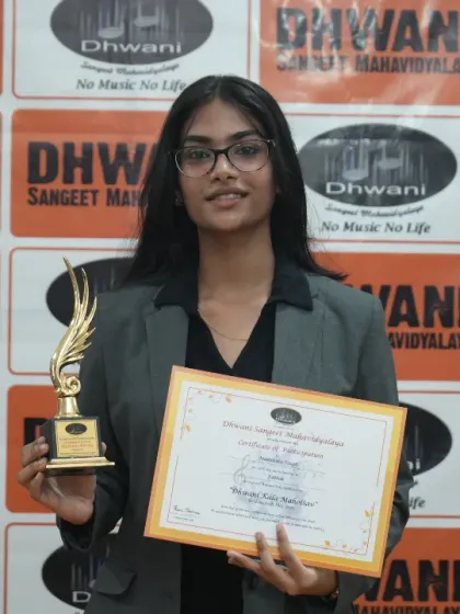 A young woman proudly holds her certificate and trophy.