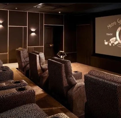 This theater features unique animal-print fabric on its tiered recliners, demonstrating our ability to customize designs to your specific taste. The elegant wall sconces and dark panels create a chic, boutique cinema feel.