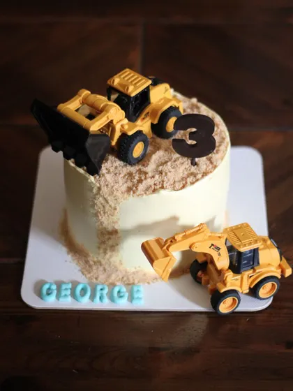 A construction theme cake for a little builder's party. The "dirt" is made from crushed cookie crumbs, and the toy trucks make for a fun, interactive cake that the birthday boy can play with afterward.