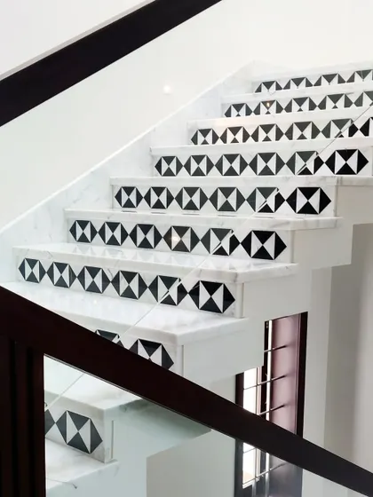 A staircase can be a canvas for creativity. Here, we used black and white marble inlay on the risers to create a bold, geometric pattern that adds a graphic and modern touch to a traditional element.