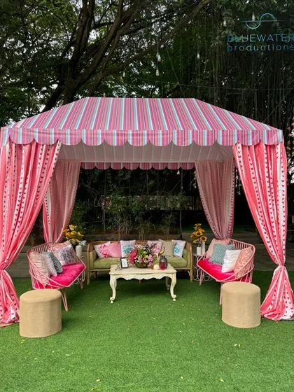 A charming pink striped gazebo provides a perfect photo-op or a cozy corner for guests to relax during the daytime festivities.
