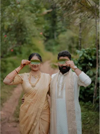 A playful portrait of the couple in nature, holding leaves over their eyes, showcasing their fun and creative side.