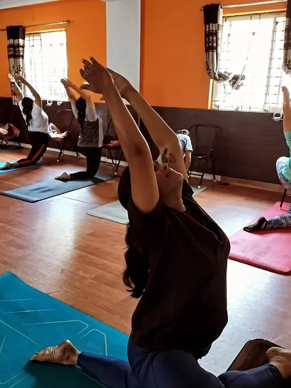 This photo captures the collective focus in a deep stretching class. Everyone is working at their own level, using chairs and the floor to find their personal expression of the pose.