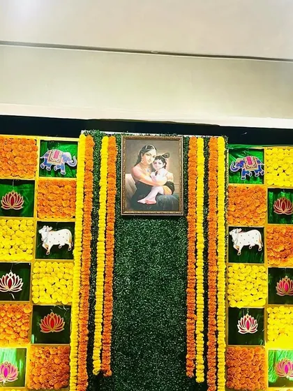 A close-up of a traditional Seemantham backdrop. The design features a checkerboard of marigolds, auspicious motifs, and a central portrait, creating a rich and meaningful decoration.