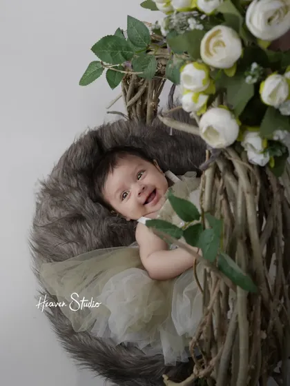 A smile that could light up the world. This newborn is captured in a rustic twig nest, surrounded by delicate white flowers for a natural, earthy feel.
