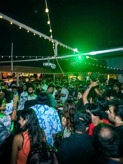 The rooftop packed under green lights. The lighting and ambiance change as the night progresses.
