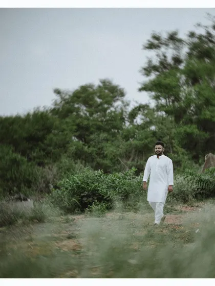 A motion-blur shot of the groom walking through a field, creating a dynamic and artistic pre-wedding portrait.
