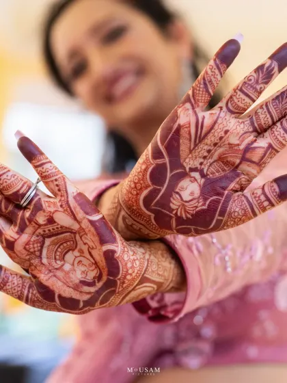 A bride proudly displays her detailed Mehendi, which often includes personalized elements like the groom's portrait. This shot is a celebration of the artistry and the love story woven into the henna.