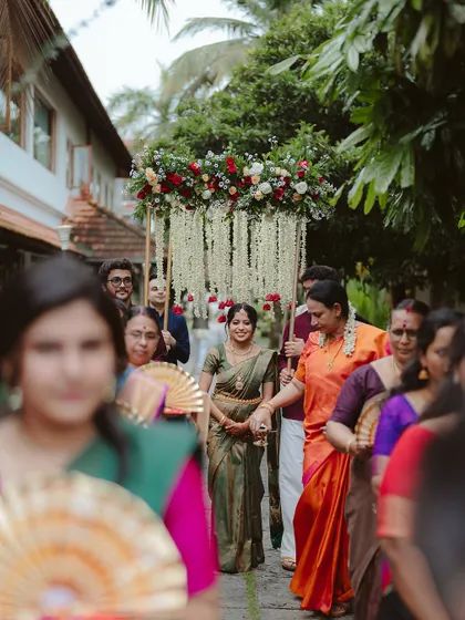 The bride's grand entrance under a canopy of flowers. This shot, taken from behind the crowd, creates a sense of anticipation and focuses on the beautiful tradition.
