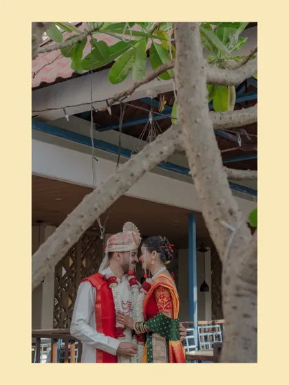 An artistically framed shot of a Maharashtrian couple, seen through a tree's branches, creating a sense of intimacy and natural beauty.