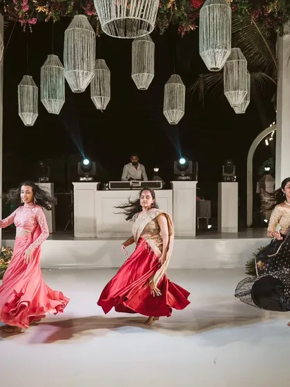 The bridesmaids' synchronized dance is a highlight of the Sangeet. The stage is set with beautiful hanging lanterns, providing a perfect backdrop for the performances.
