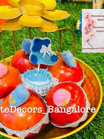 A colorful baby shower platter with decorated pomegranates and a blue baby sock cutout. I can customize these details based on your theme.