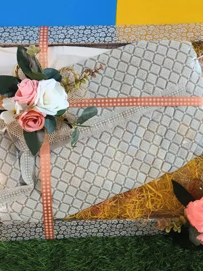 A lace suit packed in a tray with yellow shredded paper, giving it a rustic and charming look.