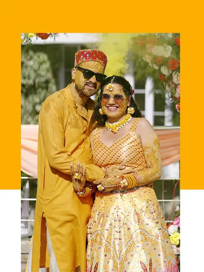 A fun and colorful portrait of the couple after their Haldi ceremony, covered in turmeric and smiling for the camera.