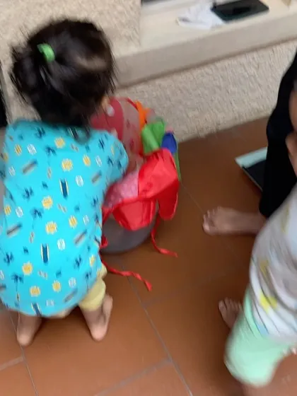 Two toddlers work together to put toys away. Learning to clean up is a practical life skill that builds responsibility and respect for our shared play space.