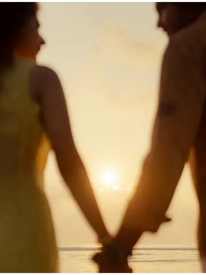 An abstract, motion-blur shot of the couple holding hands against a sunset, creating a dreamy and artistic representation of their bond.
