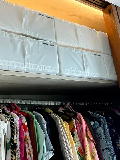Using large, labeled storage bins on the top shelf is a great way to store seasonal or less-frequently used items like winter wear, keeping them protected and out of the way.