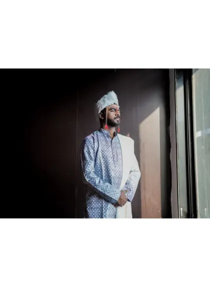 A dramatic, low-key portrait of the groom looking out a window, a moment of quiet contemplation.