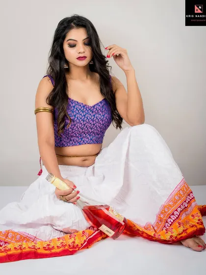 A conceptual shot titled 'Nasha' (Intoxication). The model, in an ethnic-inspired outfit, sits with a bottle of rose wine, her expression hinting at a story of indulgence and emotion.