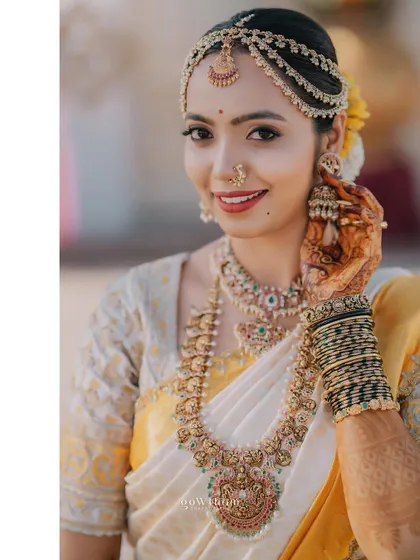 Adjusting her earring, this bride looks picture-perfect. The image highlights the detailed jewellery and the flawless makeup that enhances her features.