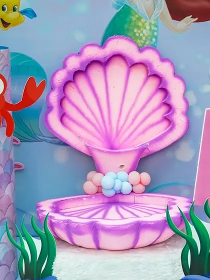 A detailed shot of the mermaid photo booth, featuring a large pink clamshell seat and underwater character props.