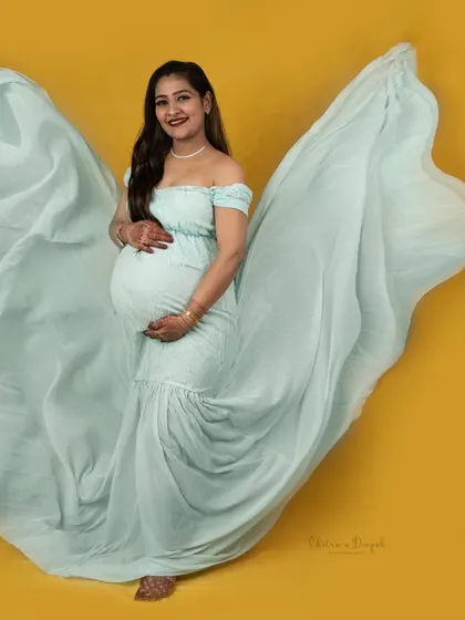 The beauty of a fabric toss. The mint green gown flows like wings against the bright yellow background, creating a dynamic and joyful image.