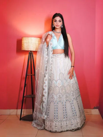 A full-length shot of the white and blue lehenga, a versatile choice for any wedding guest.