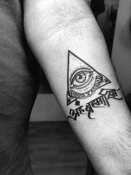 The sacred Sanskrit phrase "Aham Brahmasmi" paired with an all-seeing eye within a triangle. This inner forearm tattoo combines spiritual text with powerful symbolism.