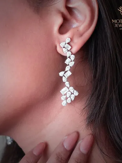 These chandelier earrings feature a cascade of multi-shaped diamonds, creating a waterfall of light. They are designed to be showstoppers, perfect for the most glamorous occasions.