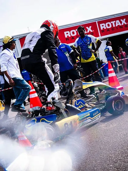 A driver jumps into his kart in the pit lane, ready to head out.