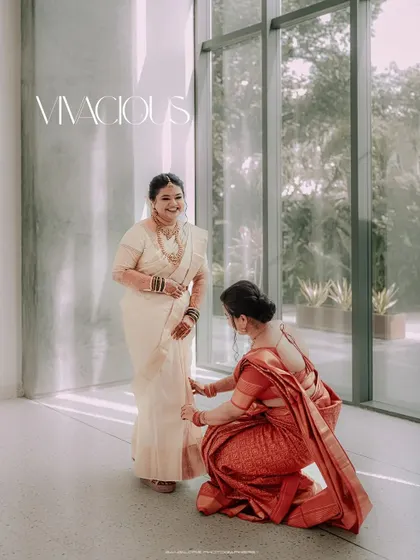 A helping hand from a loved one. This candid moment of a bridesmaid or mother adjusting the bride's saree is a beautiful story of support and love.