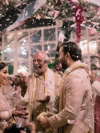 The moment of joy and celebration as flower petals shower the happy couple. We designed this contemporary mandap with mirrored arches inside a glasshouse to reflect the light and happiness of the pheras.
