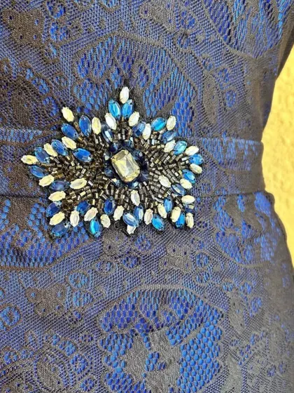 A close-up of the beautiful star-shaped embellishment on this blue and black lace cocktail dress.