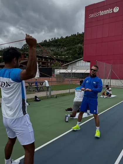 A typical day at the office during the Davis Cup in Switzerland. Here, I'm guiding an athlete through resistance band exercises for shoulder activation and stability, a crucial pre-practice routine for tennis players.