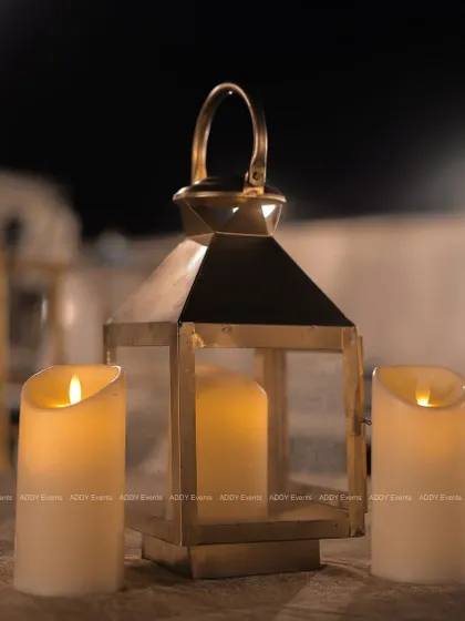 We use ambient lighting to create a cozy and intimate atmosphere. This simple arrangement of a rustic brass lantern and flameless pillar candles adds a warm and inviting glow to tablescapes.