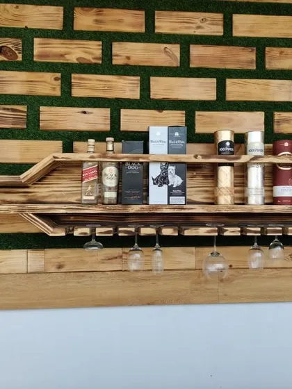 This close-up shows the detail of the bottle-shaped shelf, fully stocked. It demonstrates the unit's practical use for storing various bottles and glassware, blending art with utility.