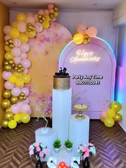 An anniversary decoration in my party hall, featuring a yellow and pink balloon arch and a "Happy Anniversary" neon sign.