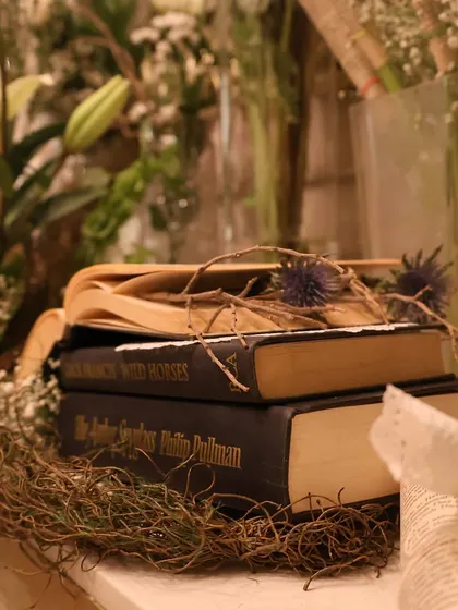 A detail shot focusing on the props within our decor. A stack of classic books, a nest of dried twigs, and delicate thistles come together to build a rich, textured narrative.