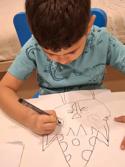 This photo captures a moment of intense focus as a young artist carefully outlines his drawing. This is the first step in our process, building a strong foundation for the final piece.