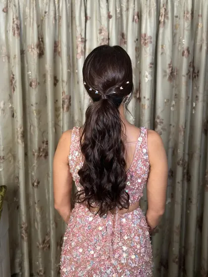 A view of the chic hairstyle, a wavy ponytail with delicate pearl accessories that add a touch of modern elegance to the Sangeet look.