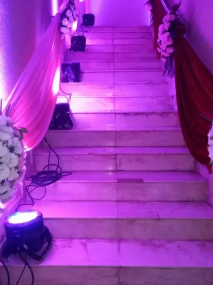 Staircase decoration for a wedding venue. We used drapes in pink and red fabric along the railings, accented with white floral bouquets and purple uplighting to make the entrance grand.