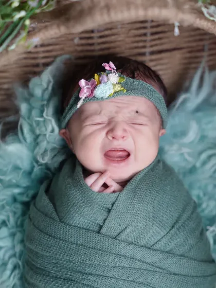 Even a little cry can make for an adorable and authentic photo. This newborn is showing off her tiny yawn or cry, a classic baby moment.