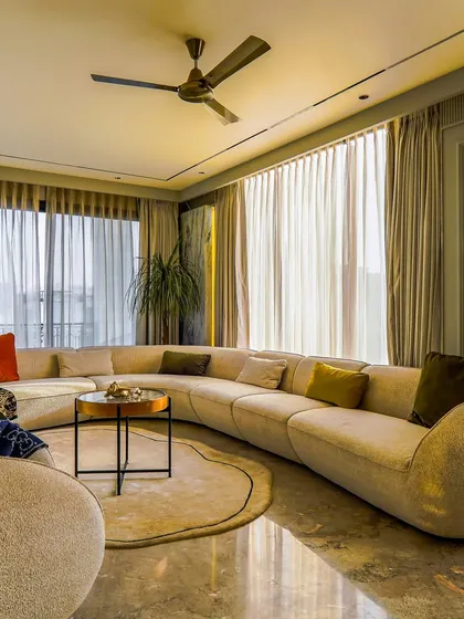 The large curved sofa is the centerpiece of this comfortable living room. It’s an inviting piece of furniture that defines the room's soft, organic feel, perfect for family gatherings.