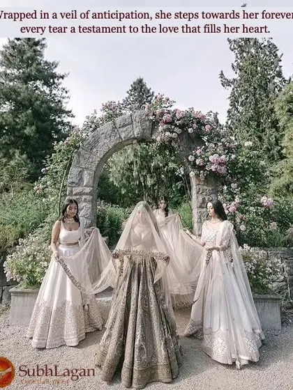 Surrounded by her bridesmaids under a beautiful stone arch, a bride is wrapped in her veil. We foster matches where the union is celebrated by the entire community.
