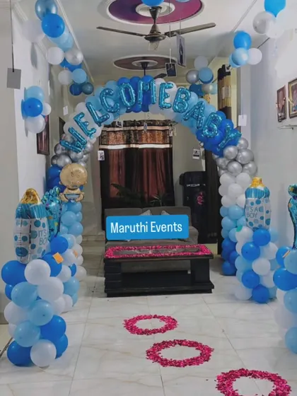 A 'Welcome Baby' entrance decoration with a blue, white, and silver balloon arch and a pathway of rose petals.