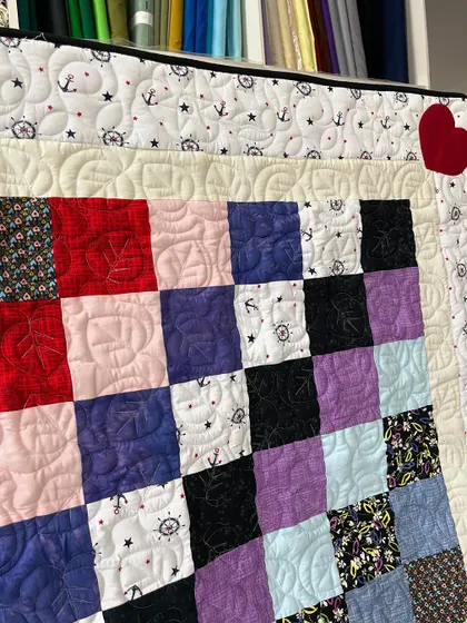 A detail shot of the assorted baby quilt, showing the mix of fabrics and the heart appliqué.