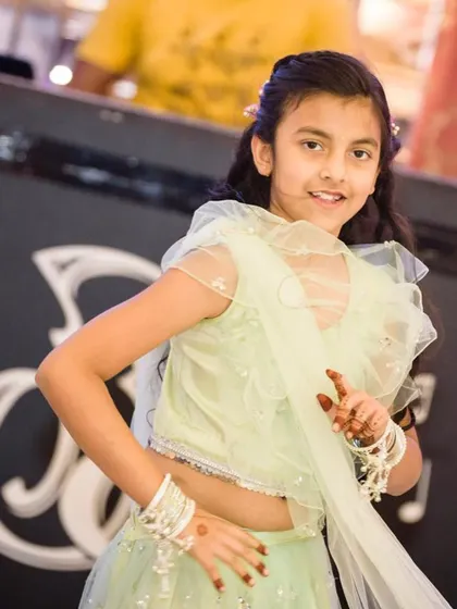 A close-up of the young girl in her mint green Mehendi outfit, showing her playful pose and the delicate details of the dress.