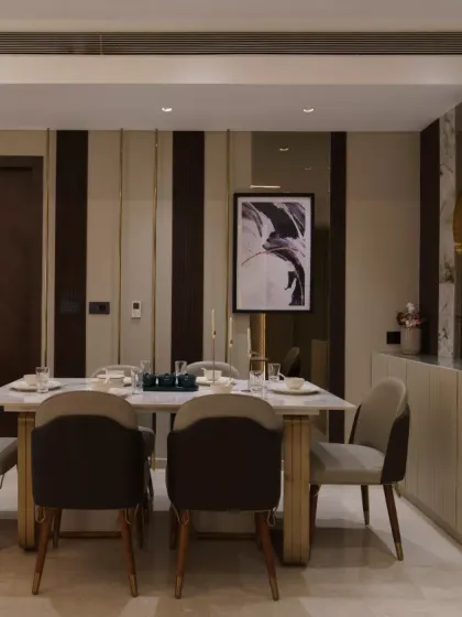 A symphony of modern elegance and understated luxury, this dining space boasts sleek marble finishes, rich wooden accents, and gilded highlights. Perfectly complemented by abstract art and refined decor, it exudes sophistication and timeless charm.