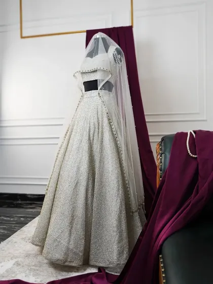 The ivory lehenga displayed on a mannequin, showing its form and structure. This allows you to see the garment as a piece of art before it is worn, highlighting the silhouette and the flow of the fabric.
